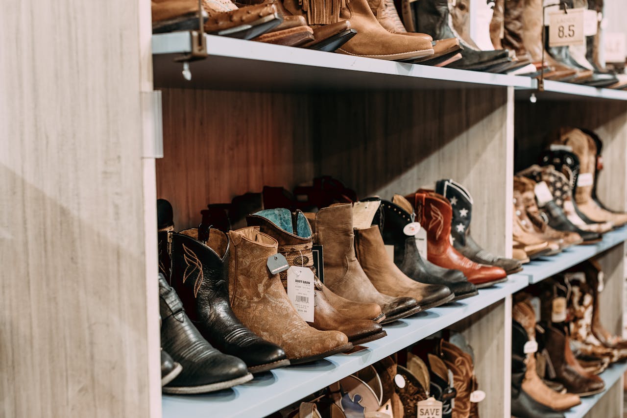 Home A variety of cowboy boots on display in a retail store, highlighting styles and material.
